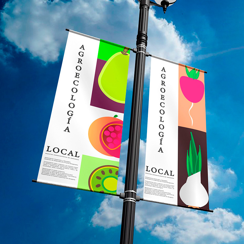 Mupi con hortalizas en una farola publicitando la agroecología local con un cielo azul de fondo